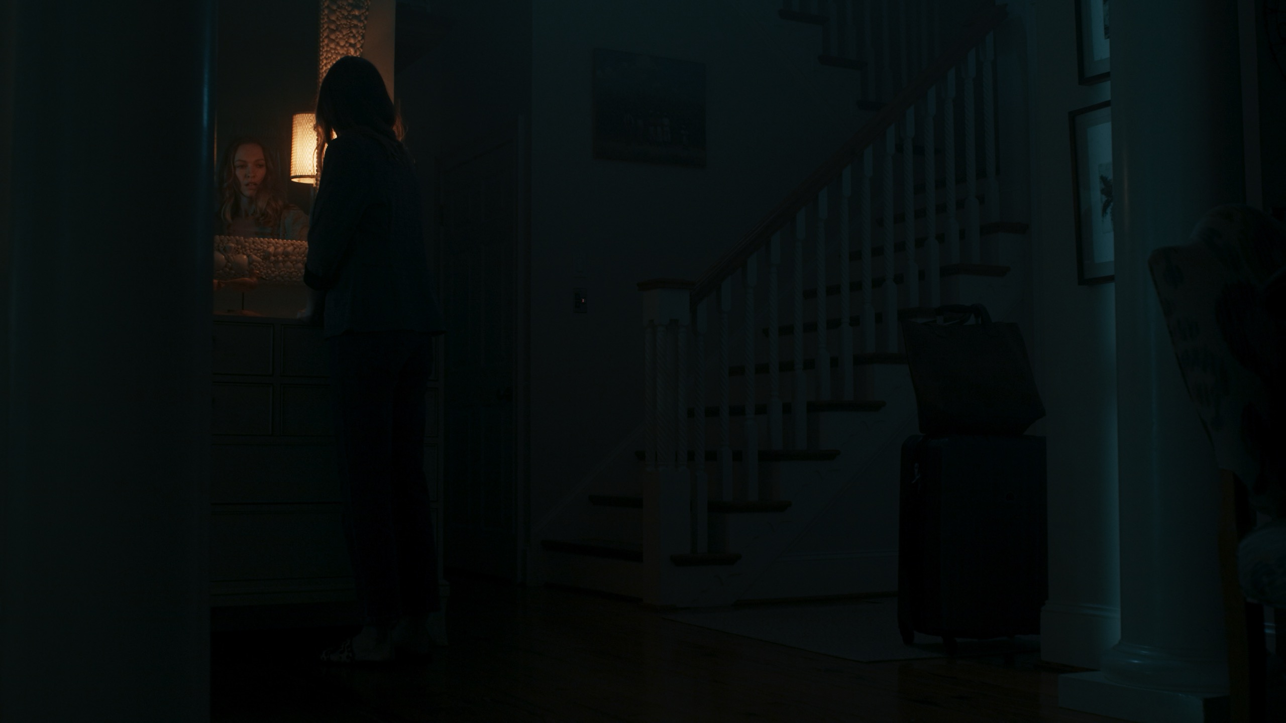 Silhouetted woman in doorway with moonlit staircase