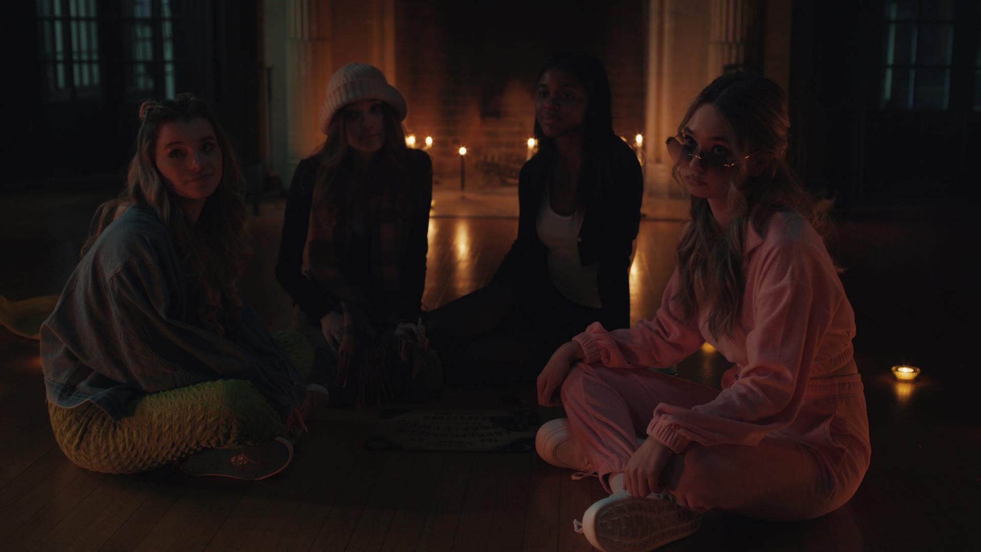 Four women sitting by firelight with candles