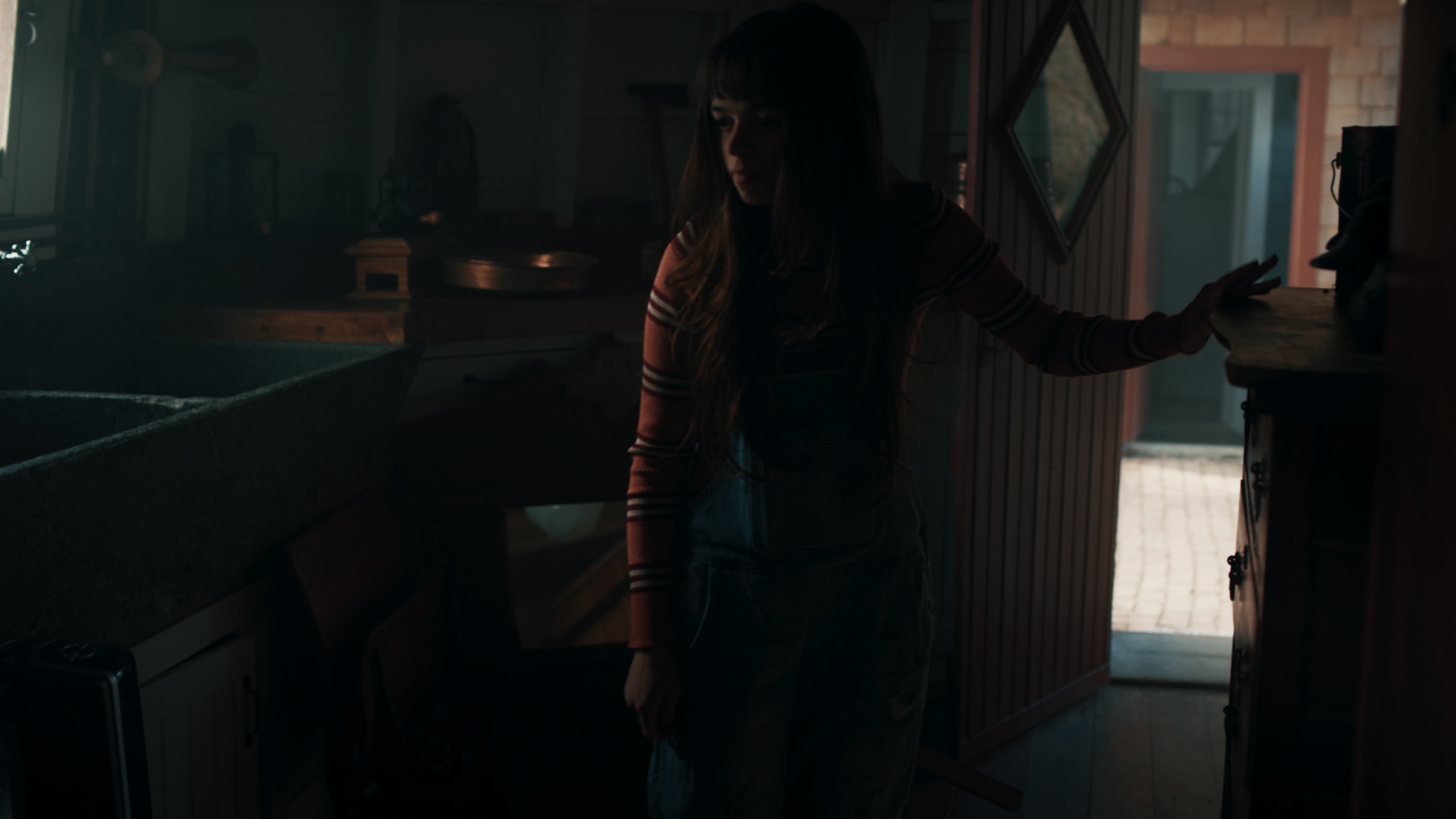 Silhouetted woman reaching toward door against backlight