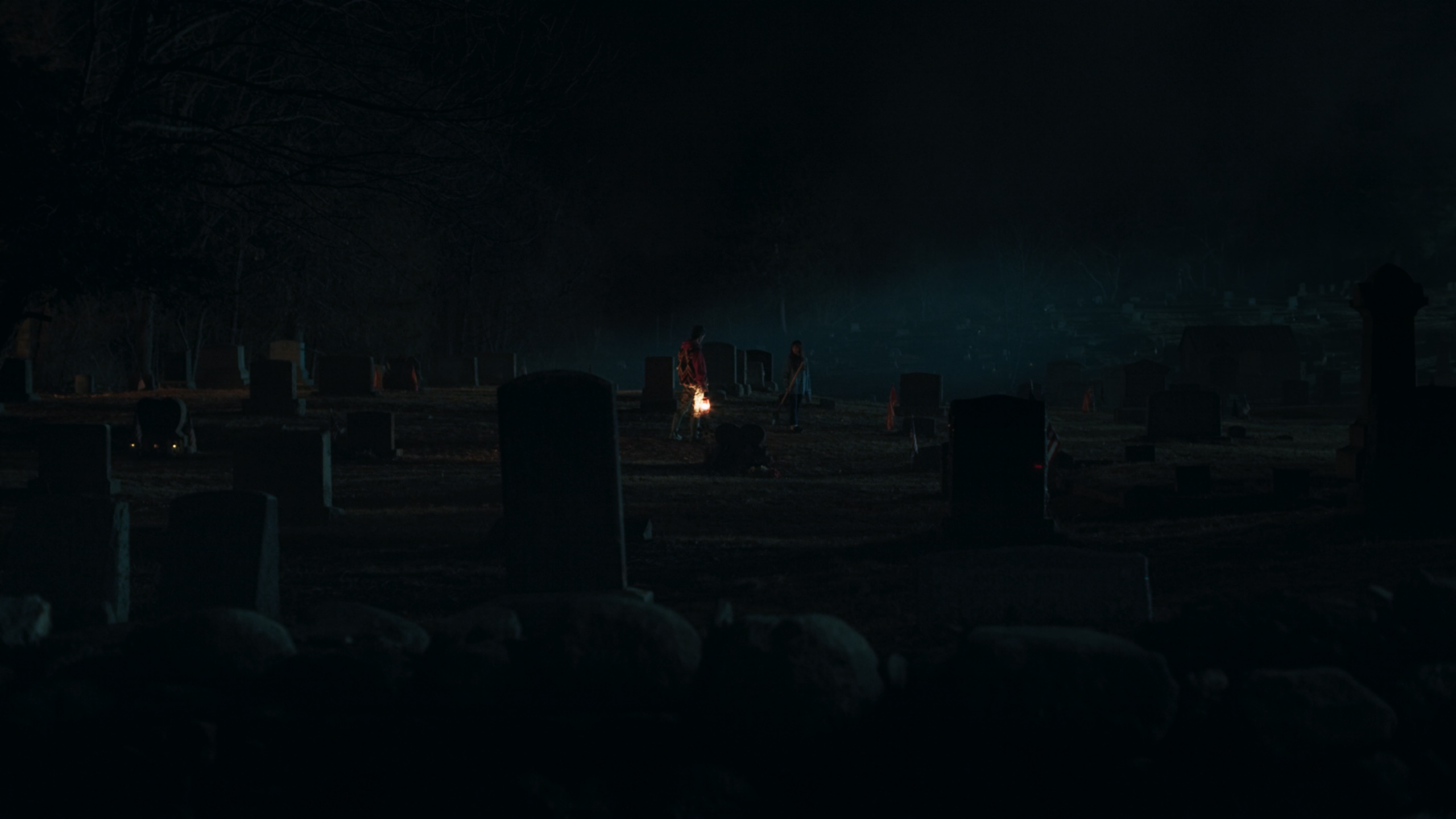 Graveyard with single lantern glowing in fog