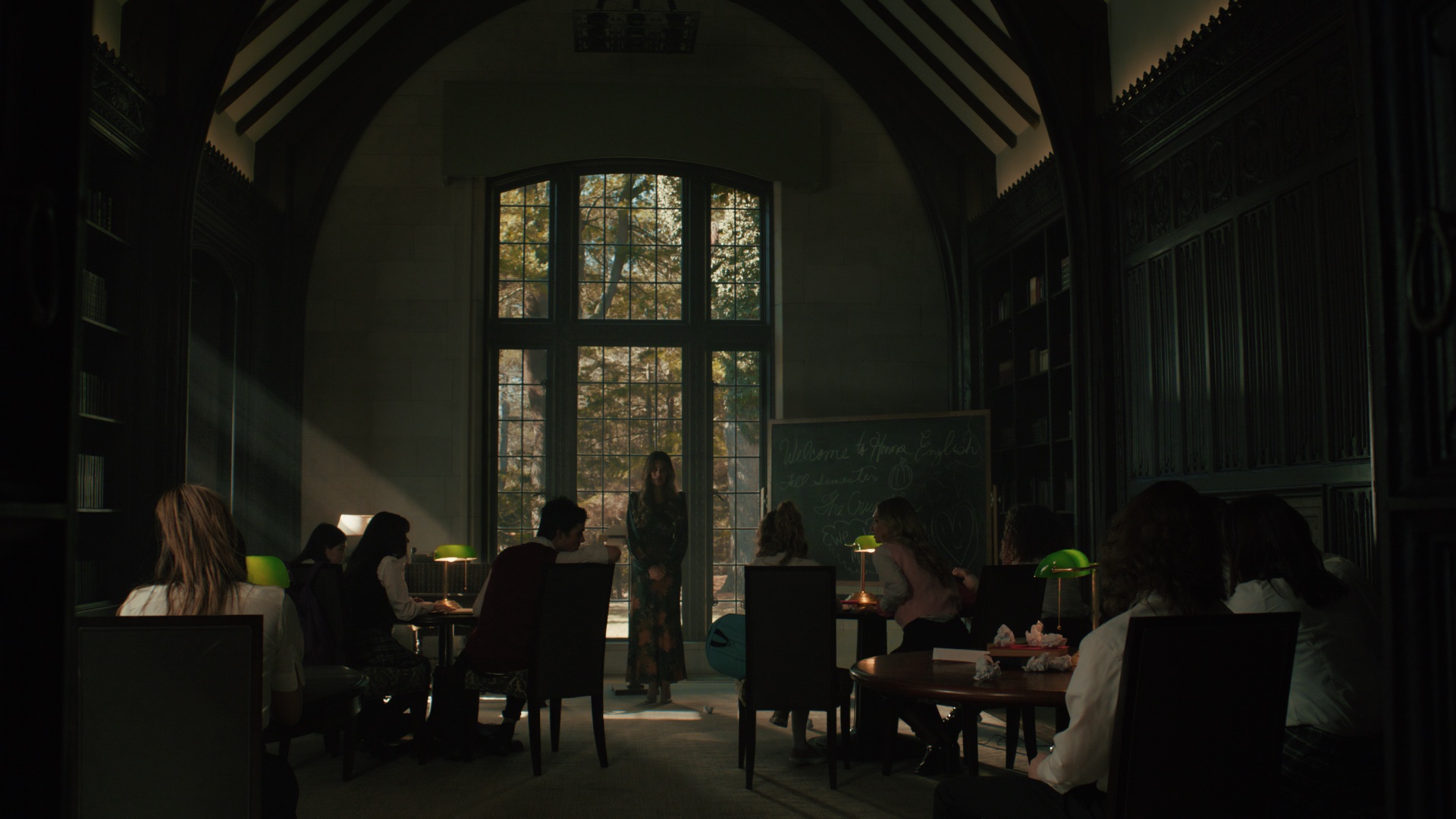 Gothic library interior with arched window and banker lamps
