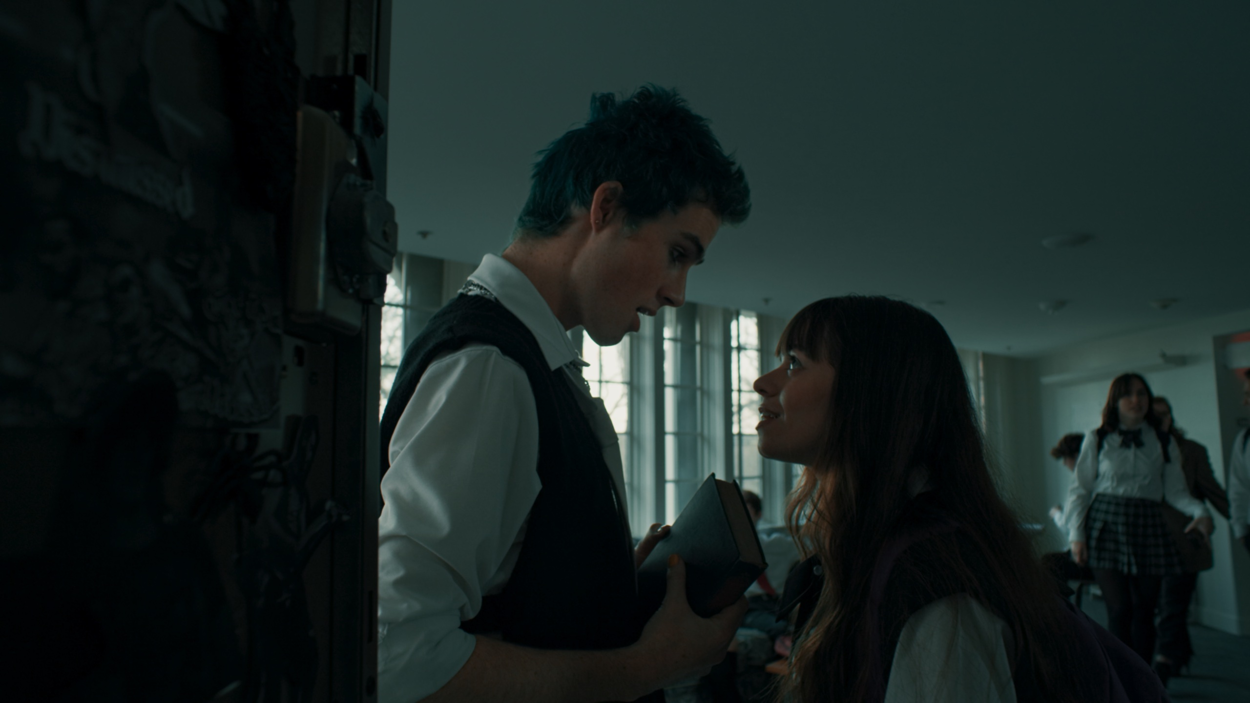 Two students by lockers in cool hallway light