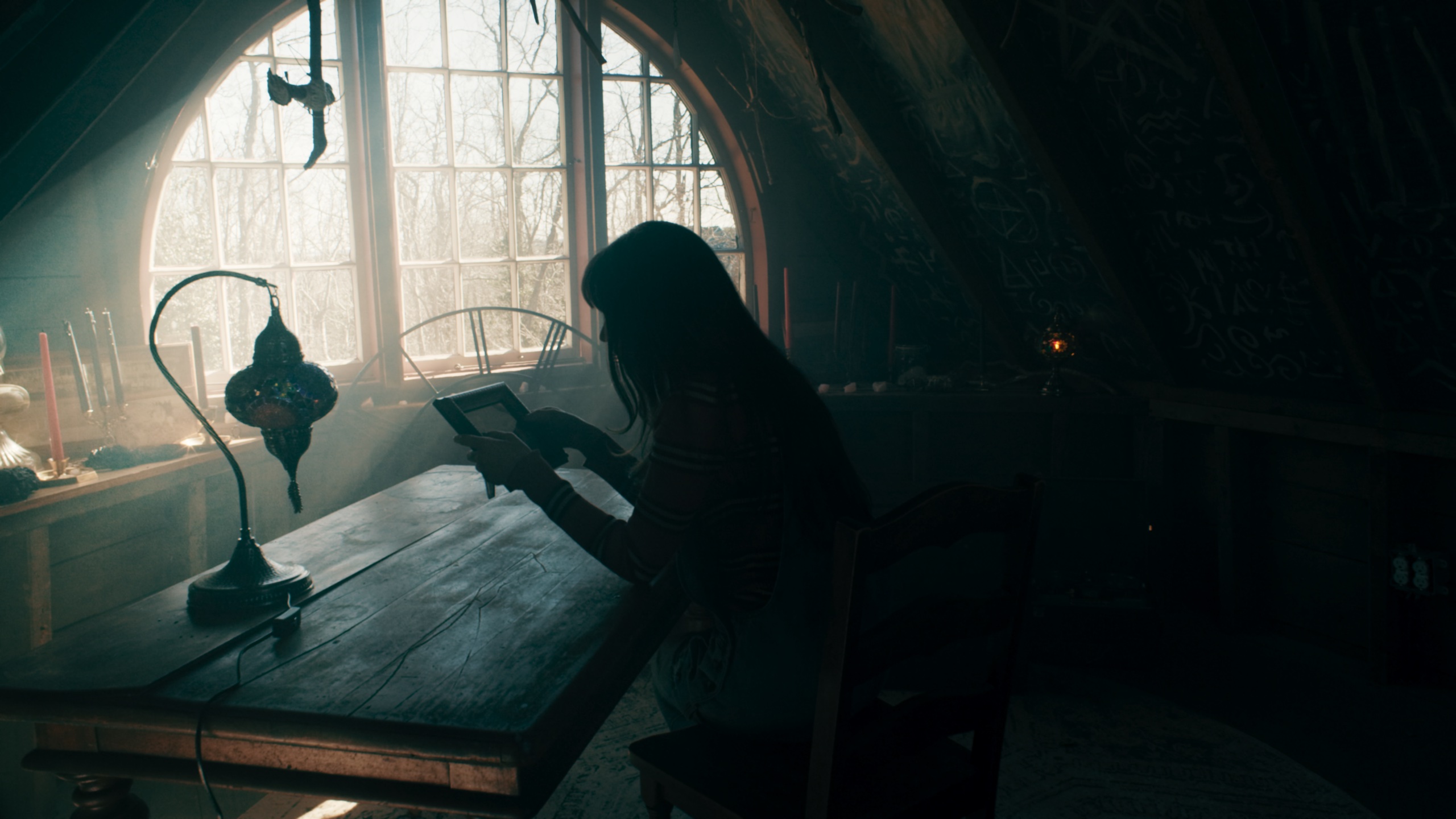Woman silhouetted at desk in attic with arched window