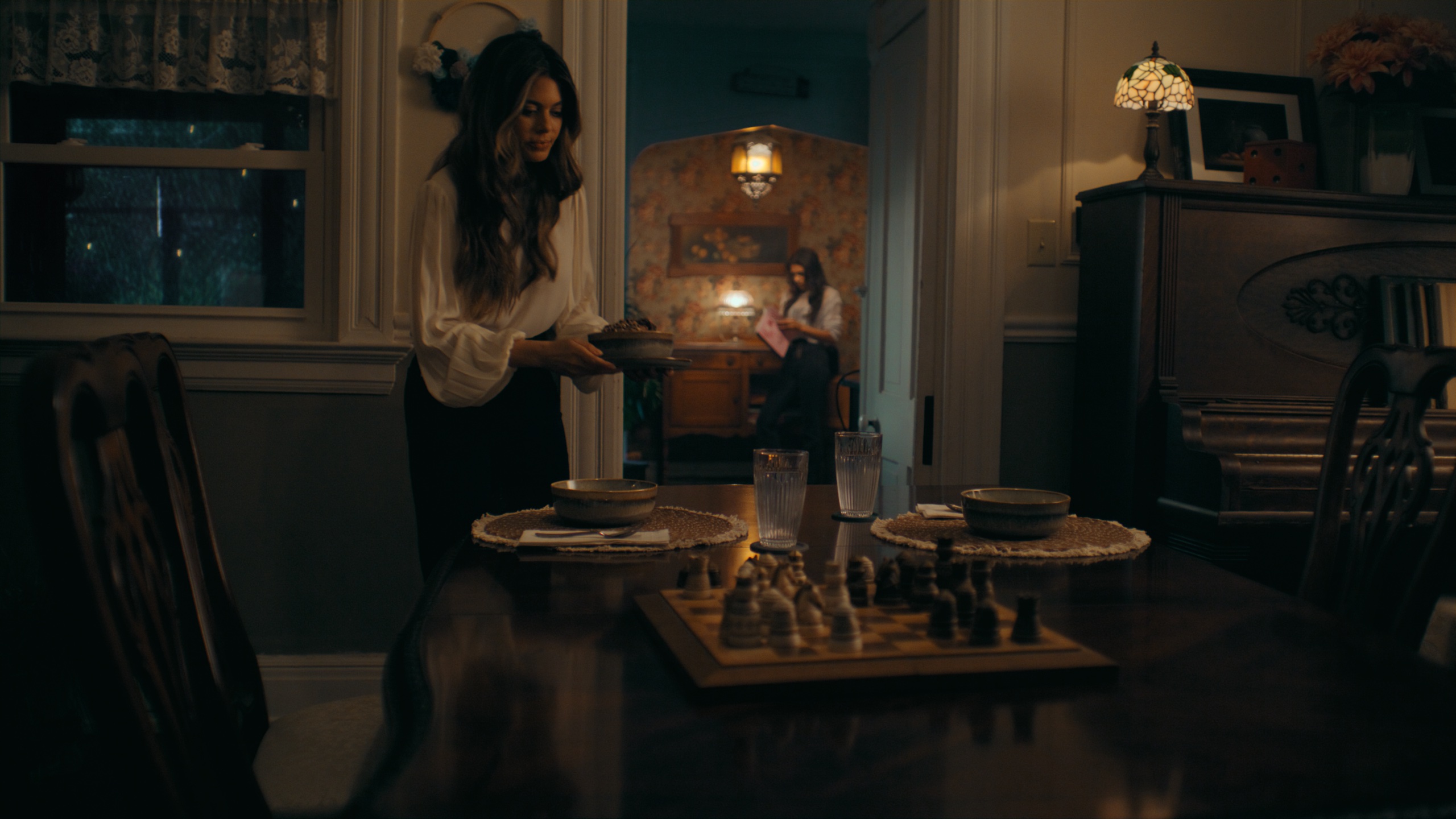 Two women in candlelit dining room with chess set
