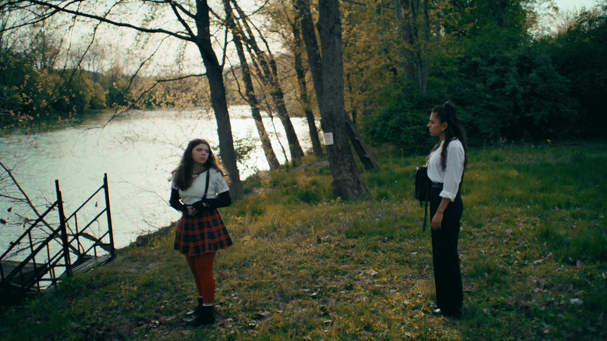 Two women on autumn riverbank near dock
