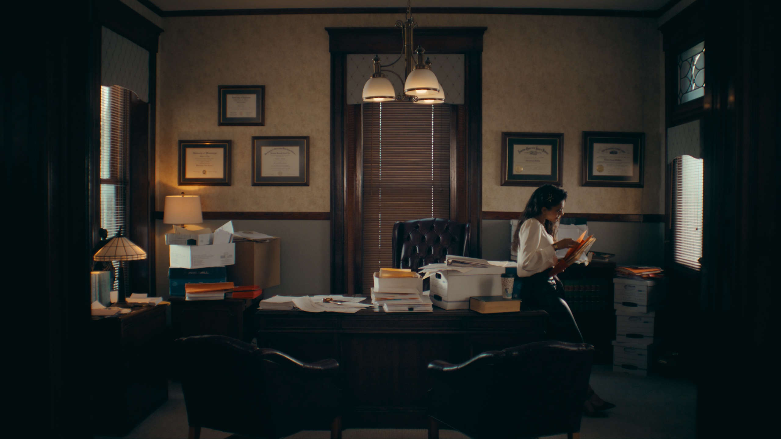 Woman reading documents in dark law office lit by desk lamps